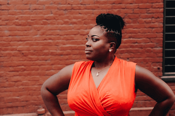Woman in an orange dress against a brick wall